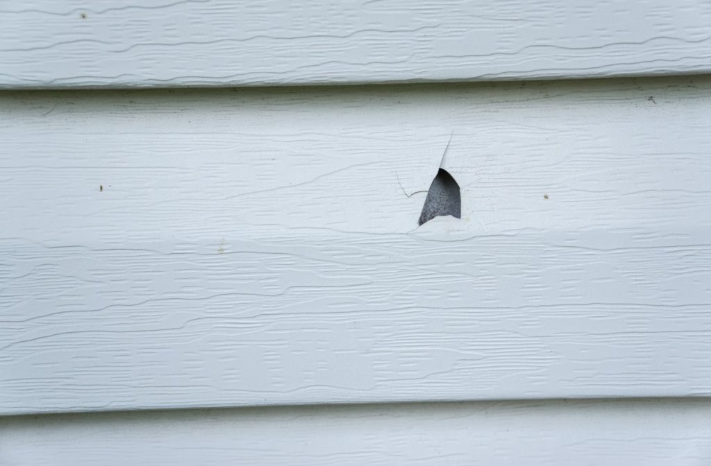 Vinyl siding which has been damaged after a hail storm