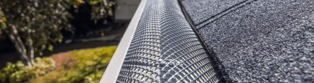 A close up view of a leaf gutter guard on a residential gutter and roof system.