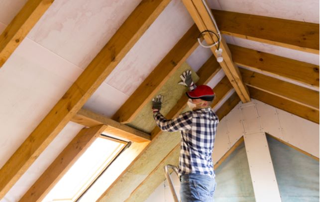 Professional man putting wood up on attic roof