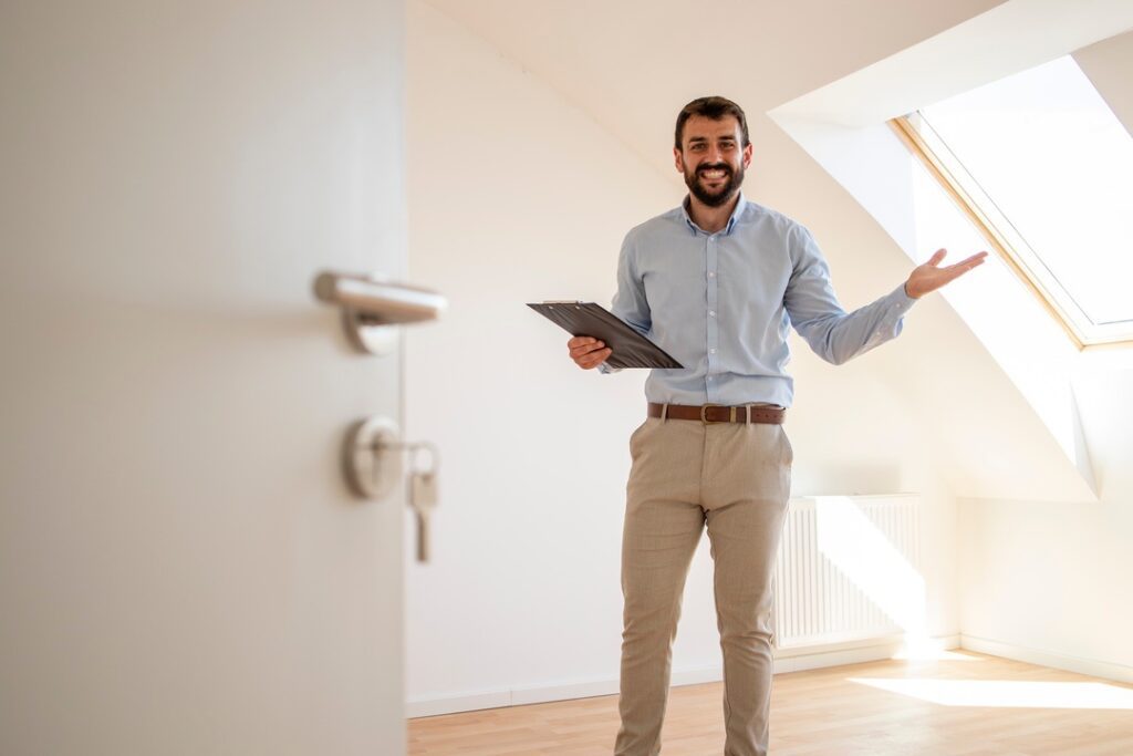 Portrait of handsome real estate agent selling new house.