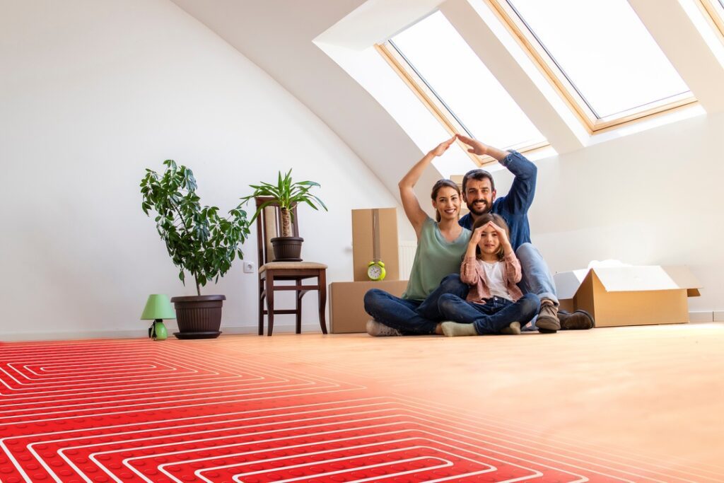 portrait of happy family sitting on warm parquet with floor heating and pipes.