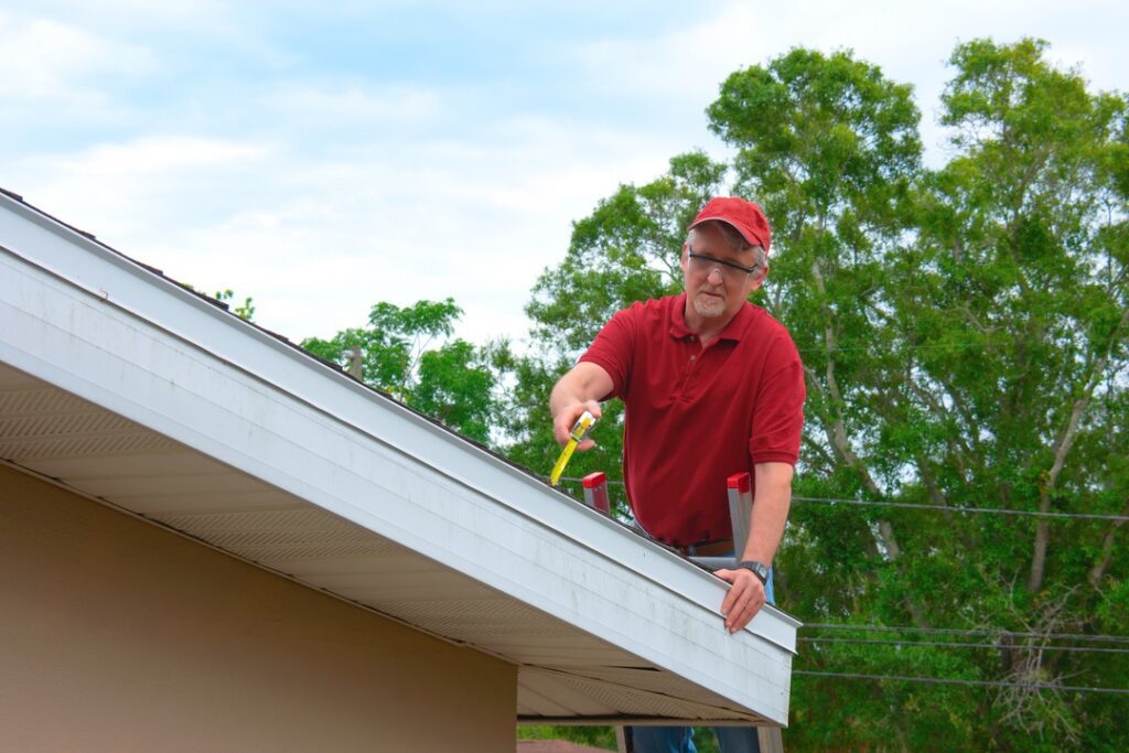 Wind mitigation inspection inspector on a ladder doing inspection on new roof to create a report and risk rating for homeowner to send to their insurance company to receive deductions in policy costs