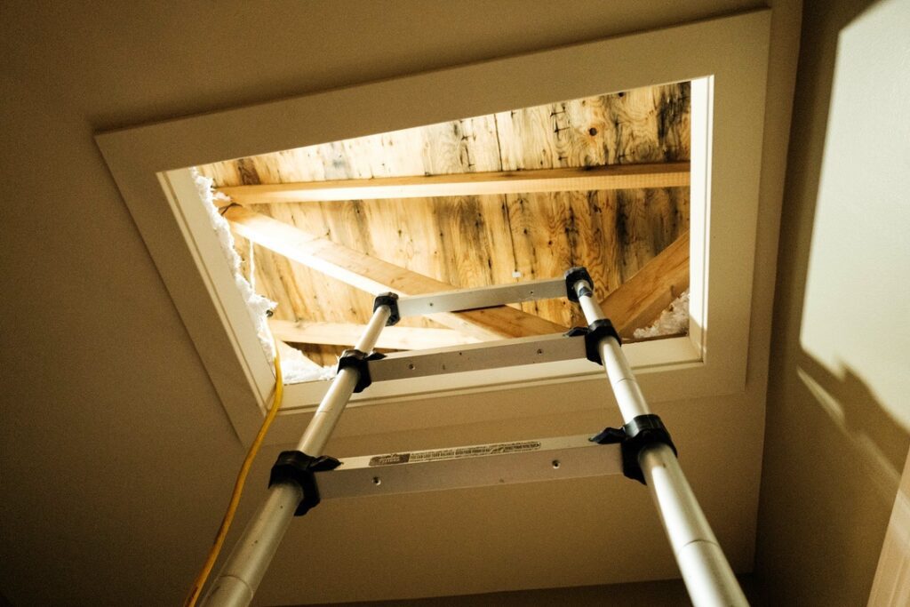 Ladder leading up to attic with water damaged materials due to attic rain