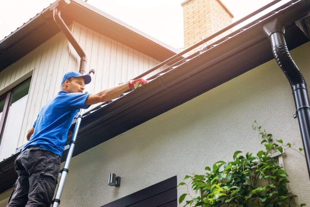 Man inspecting rooftop on ladder