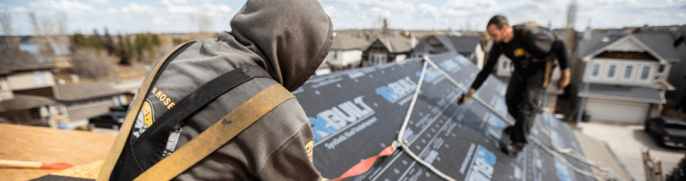 A team of Guns N Hoses installation technicians pictured in full safety gear are measuring the space they have available for shingle installation.