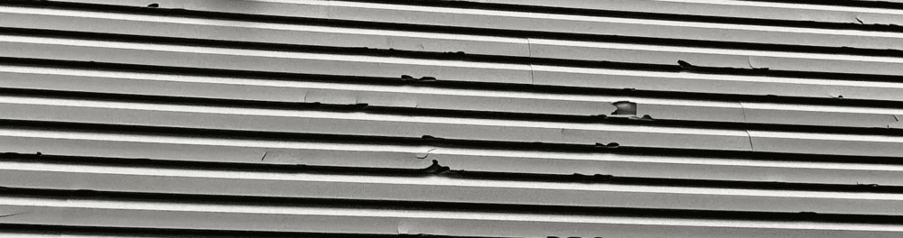 A zoomed-in view of siding damage due to hail. You can see the insulation poking through some of the holes. An example of extensive damage.